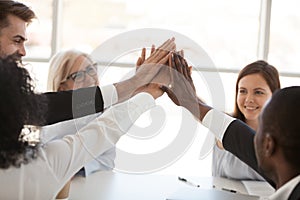 Diverse employees team giving high five at meeting close up