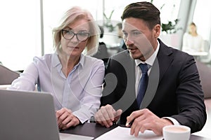 Diverse employees work on laptop discuss business ideas