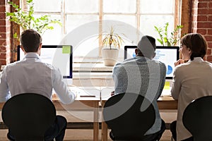 Diverse employees working together on computers in office, rear view