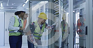 Diverse engineers with papers working in control center between racks