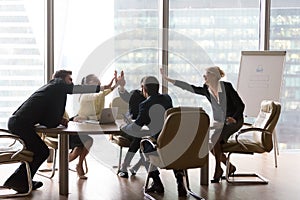 Diverse executive business team give high five in modern office