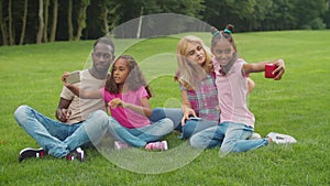 Diverse family with girls taking selfie in park