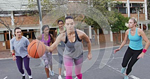 Diverse female basketball team playing match, dribbling ball
