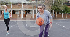 Diverse female basketball team playing match, dribbling ball