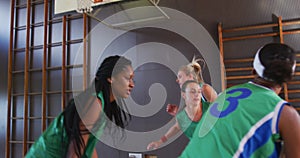 Diverse female basketball team playing match, dribbling and shooting ball