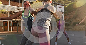 Diverse female basketball team playing match, dribbling and shooting ball