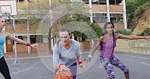 Diverse female basketball team playing match, dribbling and shooting ball