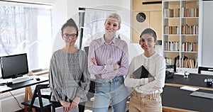 Diverse female colleagues posing threesome for corporate album in office