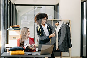 Diverse female fashion designers at work with tailor centimeters on necks and holds tablet and smartphone. independent creative