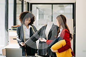 Diverse female fashion designers at work with tailor centimeters on necks and holds tablet and smartphone. independent creative