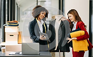 Diverse female fashion designers at work with tailor centimeters on necks and holds tablet and smartphone. independent creative