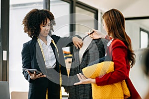 Diverse female fashion designers at work with tailor centimeters on necks and holds tablet and smartphone. independent creative