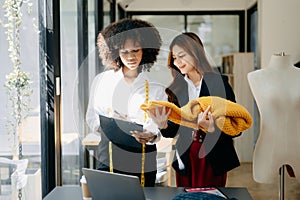 Diverse female fashion designers at work with tailor centimeters on necks and holds tablet and smartphone. independent creative