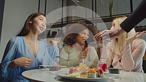 Diverse female friends deciding who paying bill at cafe