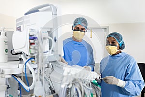 Diverse female and male surgeon studying technical equipment in operating theatre, copy space
