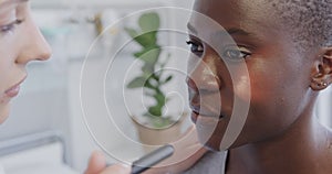 Diverse female patient and smiling doctor checking her eye with penlight in hospital, in slow motion