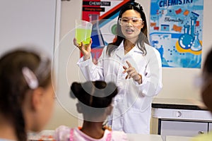 Diverse female teacher and schoolgirls with chemistry items and liquids in elementary school class