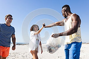 Diverse friends clean up a beach together, collecting trash