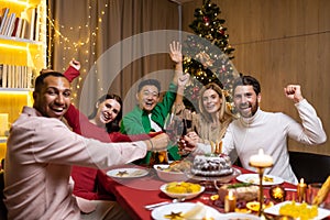 Diverse friends smiling and looking at camera group of people celebrating new year and Christmas at home sitting on