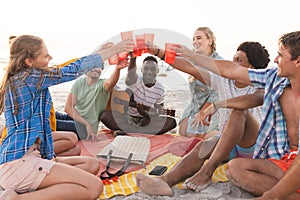 Diverse friends toast on a beach at sunset, having a party, with copy space