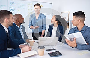 Diverse group of business people talking in a meeting and using technology and paperwork in a boardroom. Team of