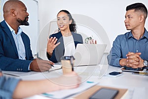 Diverse group of business people talking in a meeting and using technology and paperwork in a boardroom. Team of