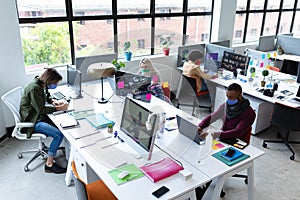 Diverse group of business people wearing face masks in creative office