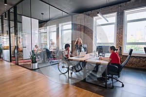 A diverse group of business professionals collaborates in a modern startup coworking center, utilizing a mix of paper