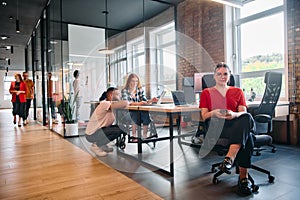 A diverse group of business professionals collaborates in a modern startup coworking center, utilizing a mix of paper