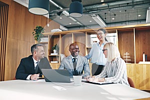 Diverse group of businesspeople laughing together around an offi