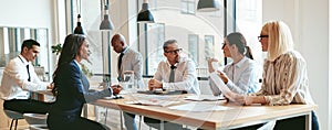 Diverse group of businesspeople talking together around an office table