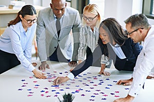 Diverse group of businesspeople working together to solve a puzz