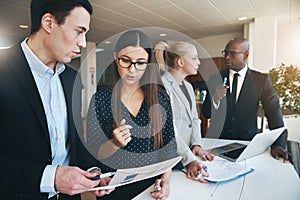 Diverse group of coworkers discussing paperwork in a modern office