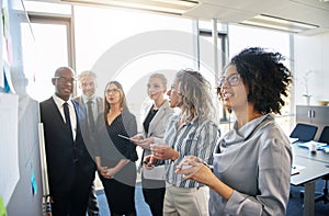 Diverse group of coworkers strategizing together on an office whiteboard