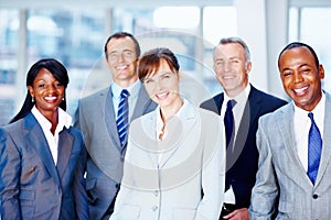 Diverse group of executives smiling. Group of diverse business men and women smiling.