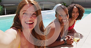 Diverse group of female friends having fun at pool taking selfie