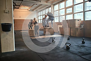 Diverse group of fit people doing box jumps together
