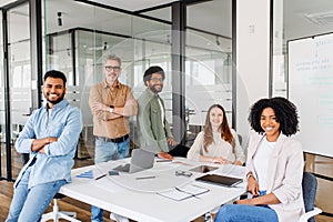 A diverse group of five colleagues beams with pride in their office