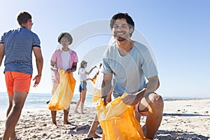 Diverse group of friends cleaning the beach and collecting trash