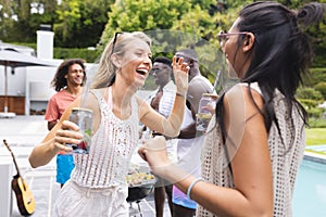 Diverse group of friends enjoying a poolside party, laughter evident