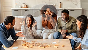 Diverse group of friends playing board game in living room