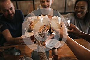 Friends sitting in a bar at night toasting with drinks