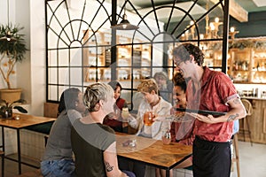 Diverse group of girlfriends ordering drinks from a bistro waiter