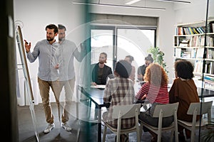 Diverse group of happy employees analyzing reports with digital device, working together in office