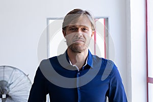 Portrait of smiling caucasian man standing in front of window in white room photo