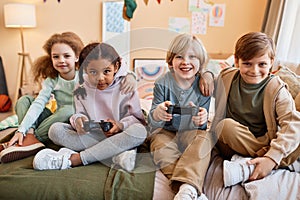 Diverse group of happy little children playing video games and having fun