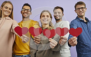 Diverse group of happy, smiling young people holding red heart shaped Valentines