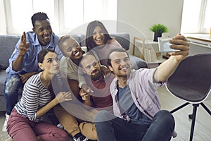 Diverse group of happy young friends taking funny selfie on mobile phone at home