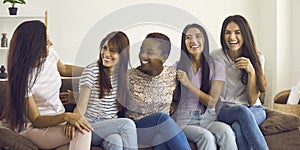 Diverse group of happy young women sitting on couch, talking and having fun together