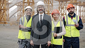 Diverse group of people building team standing outdoors in construction site smiling
